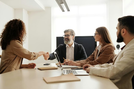 Woman greeting three professionals in a modern office setting