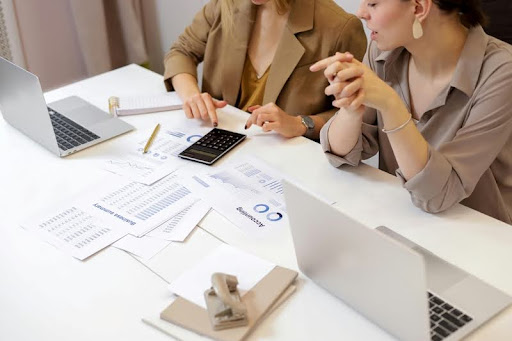 Two business women working on laptops at a desk