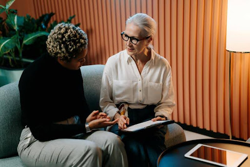 Two women discussing HR software while reviewing information on a tablet at a table.