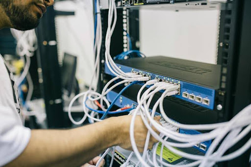 Electronic engineer adjusting cables on a server rack.