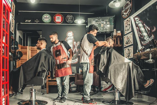 Men getting haircuts inside a modern barbershop.