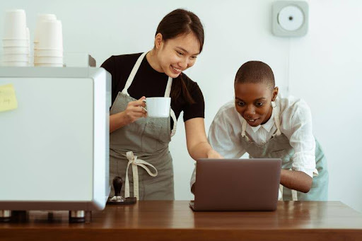 Colleagues in aprons looking at a laptop together in a kitchen