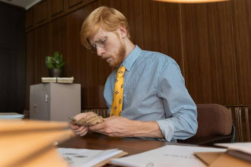 Man counting cash at his desk in a modern office