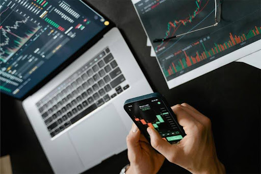 Person trading cryptocurrency on phone and laptop simultaneously