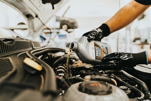 Person pouring engine oil into a car engine