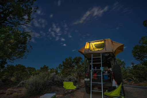 Tent illuminated at night under a starry sky in a national park.