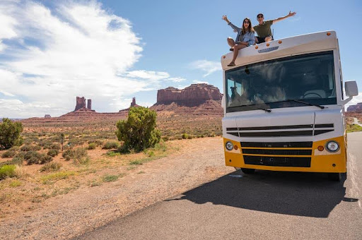 Couple sitting on top of their RV at sunset