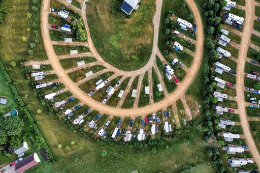 Aerial view of an RV park with full hookups surrounded by trees and open space