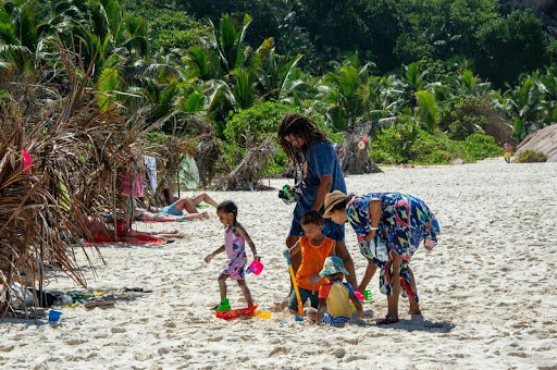 Family with young children playing together on a sunny beach.