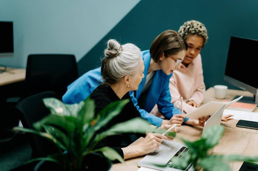 Three women having a discussion in a modern office setting
