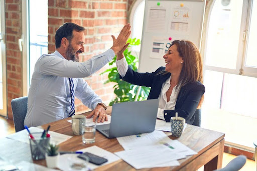 Two coworkers having a one-on-one conversation in an office setting.