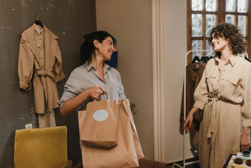Woman holding shopping bags speaking with another woman inside a retail store