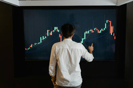 Man pointing at a screen displaying a trading graph.