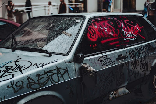 Vandalized car with broken windows and spray paint on the side