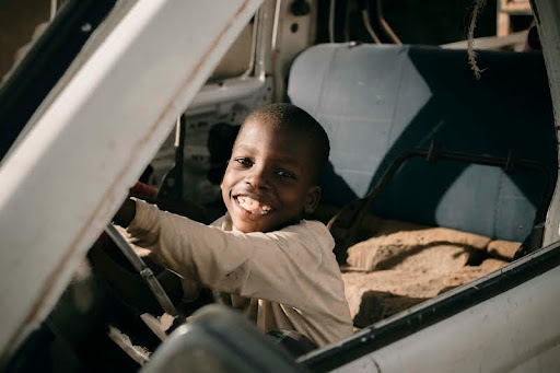 Boy sitting inside a parked car, looking out the window.