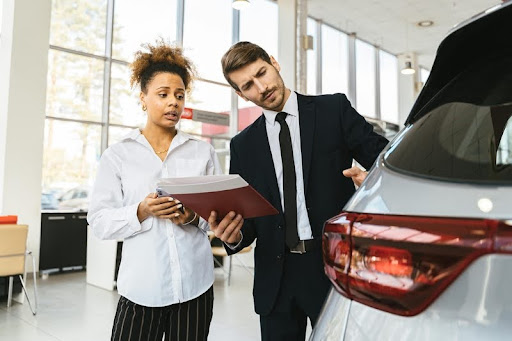 Woman speaking with a car dealer at a dealership.