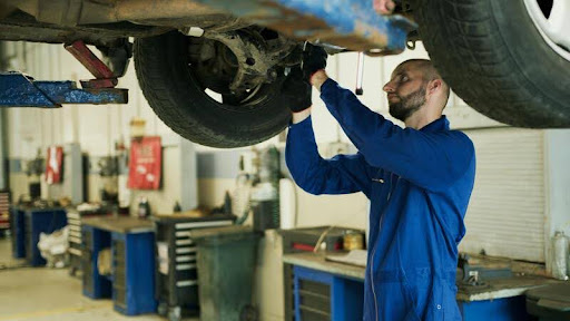 Mechanic performing routine car maintenance under the hood of a vehicle