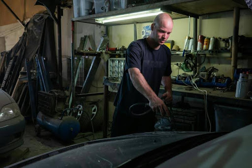 Auto mechanic working on a car in a garage.