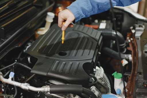 Person checking engine oil under the hood of a car