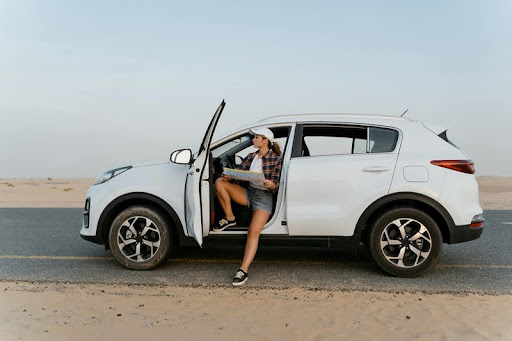 Woman sitting in compact SUV reading a map