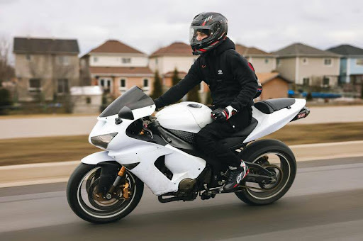 Person riding a white sports motorcycle on a paved road