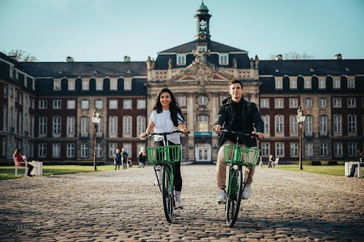 Couple riding bicycles together on a university campus pathway