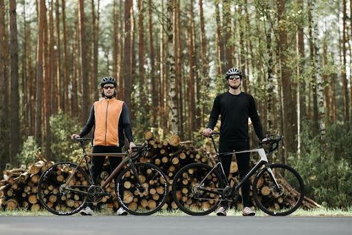 Two adults standing with their bikes in an outdoor setting.