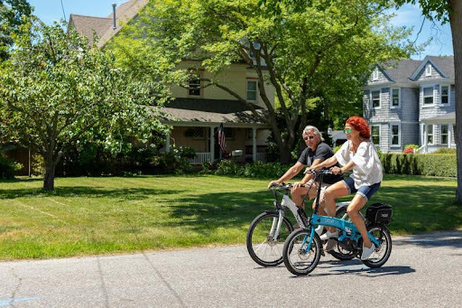 Couples riding electric bikes on a paved bike path outdoors