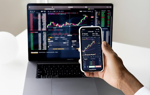 Trader using both a phone and a laptop to monitor crypto markets