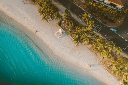 Aerial view of a sandy beach with turquoise waves and sunbathers