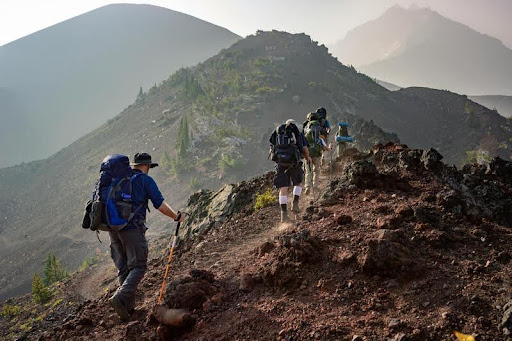 Group of hikers walking up a mountain trail on a sunny day