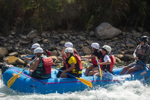 Group of people whitewater rafting through rapids on a fast-moving river