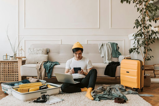 Man sitting on floor packing clothes into suitcases