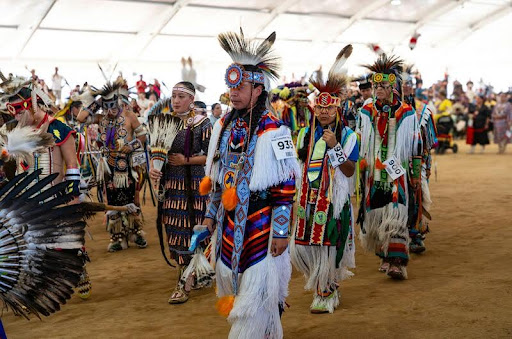 Native American dancers in traditional regalia performing at a powwow gathering.