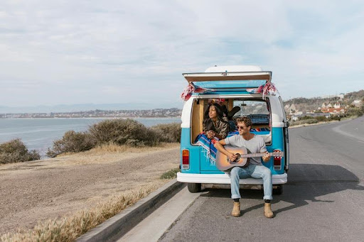 Couple sitting on top of their travel van during a weekend getaway
