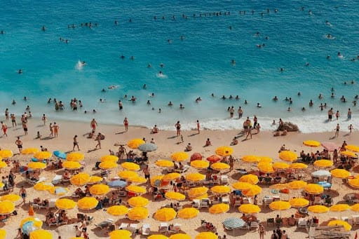 Crowded beach with people sunbathing and umbrellas packed close together