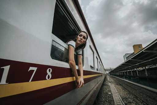 Woman leaning out of a train window with hands extended