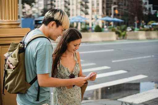 Couple standing on a sidewalk reading a paper map while traveling.