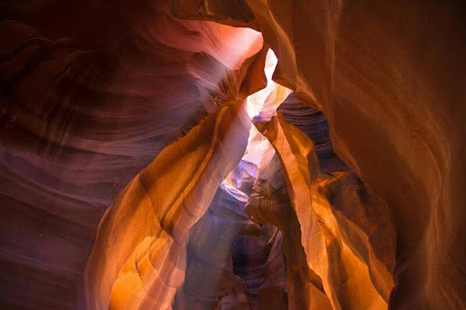 Narrow sandstone passageway with sunlight streaming through Antelope Canyon in Arizona