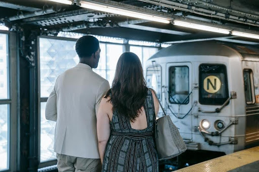 Couple standing on a train platform waiting for a train