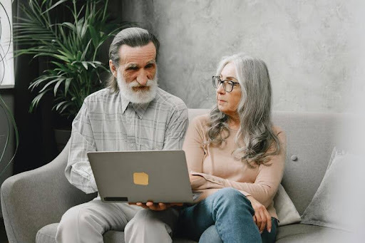 Two elderly people using a laptop together indoors