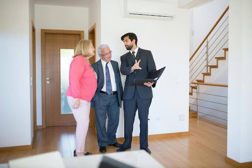 Elderly couple speaking with a real estate agent at a home.
