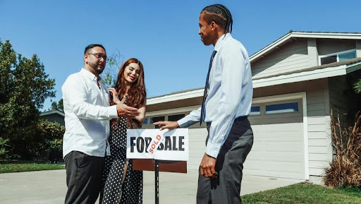 Couple standing next to a real estate agent during a home showing