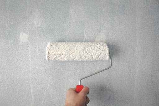 Person painting an interior wall with a roller