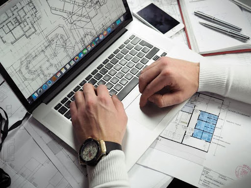 Architect designing a residential floor plan on a laptop.