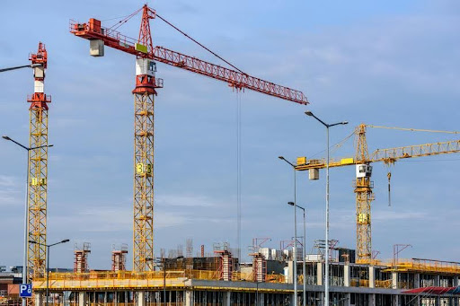 Cranes operating at a large construction site under a clear sky