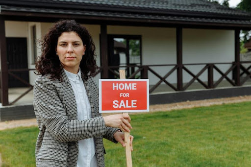 Real estate agent holding a "Home for Sale" sign