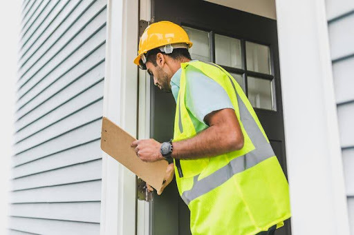 Man in a yellow safety vest inspecting the exterior of a house