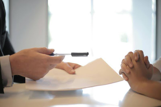 Businessman handing a woman a document to sign