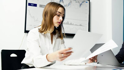 Woman in white shirt holding documents in a modern office